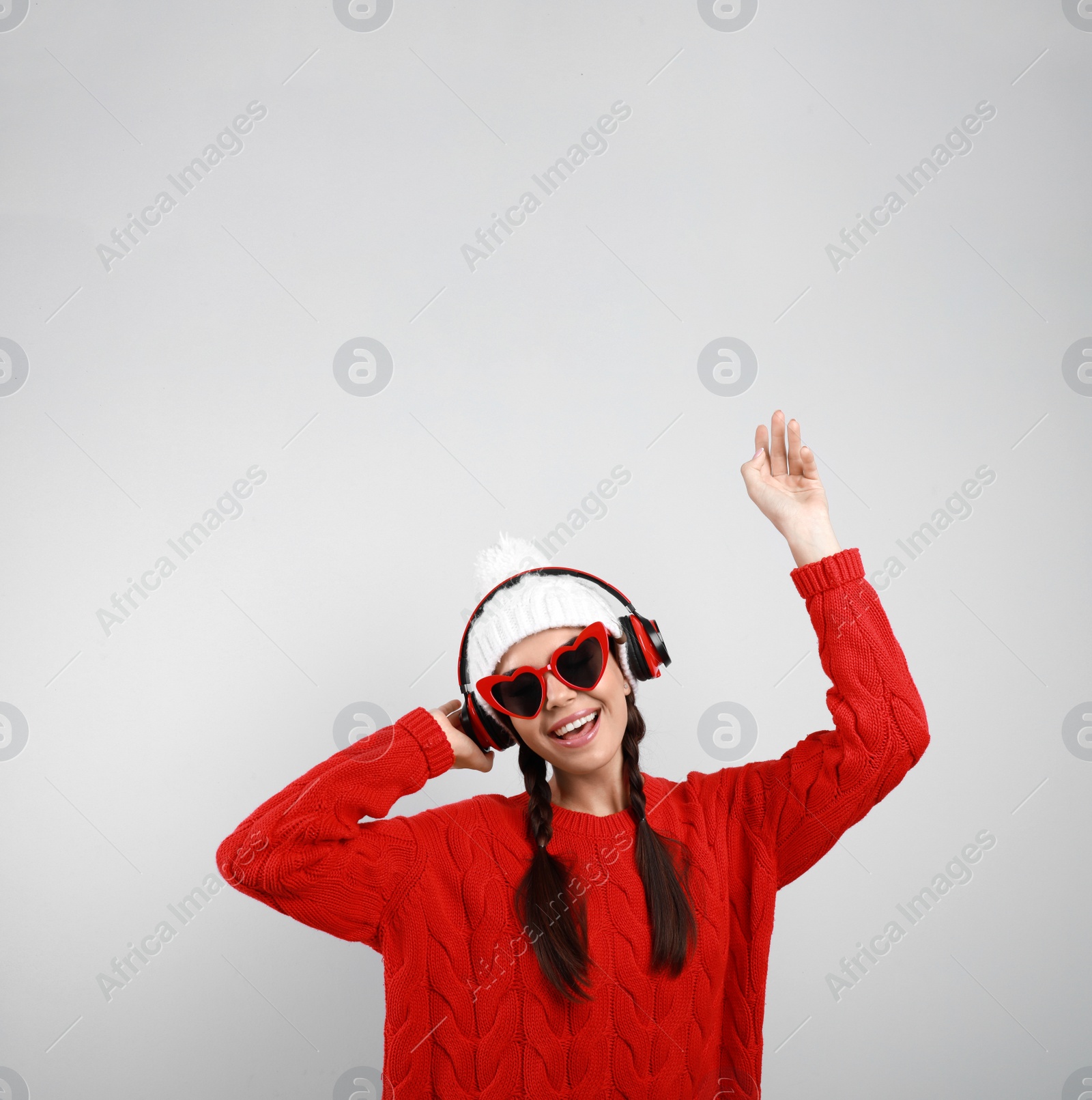 Photo of Young woman listening to music with headphones on grey background