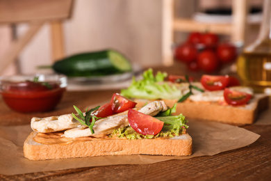 Delicious sandwiches with chicken on wooden table