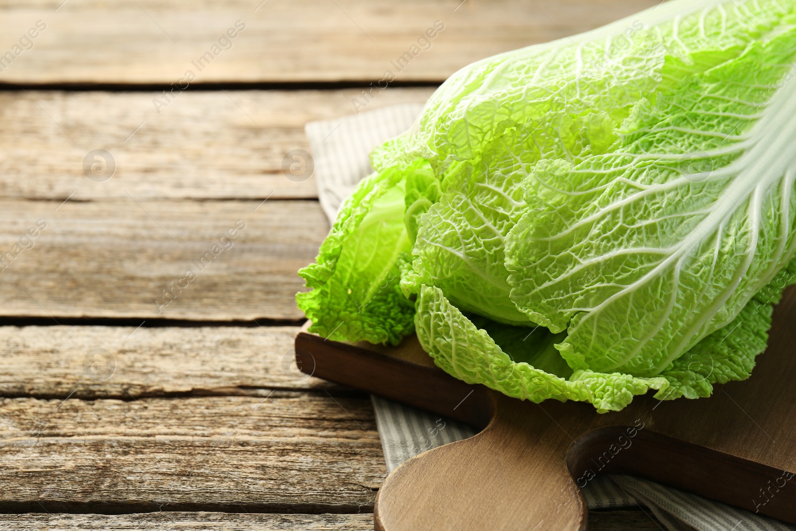 Photo of Fresh ripe Chinese cabbage on wooden table, closeup. Space for text