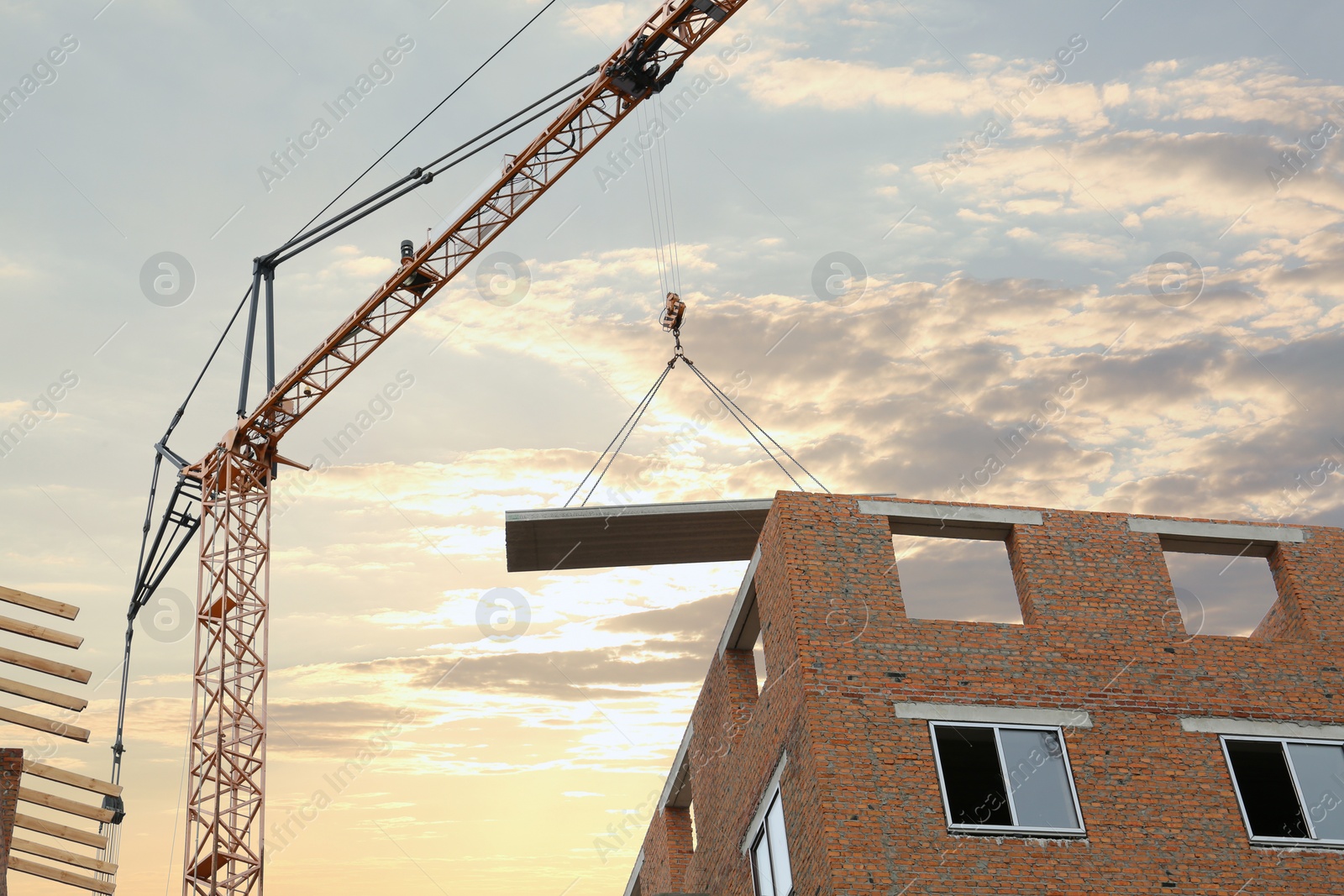 Photo of Construction site with tower crane near unfinished building, low angle view