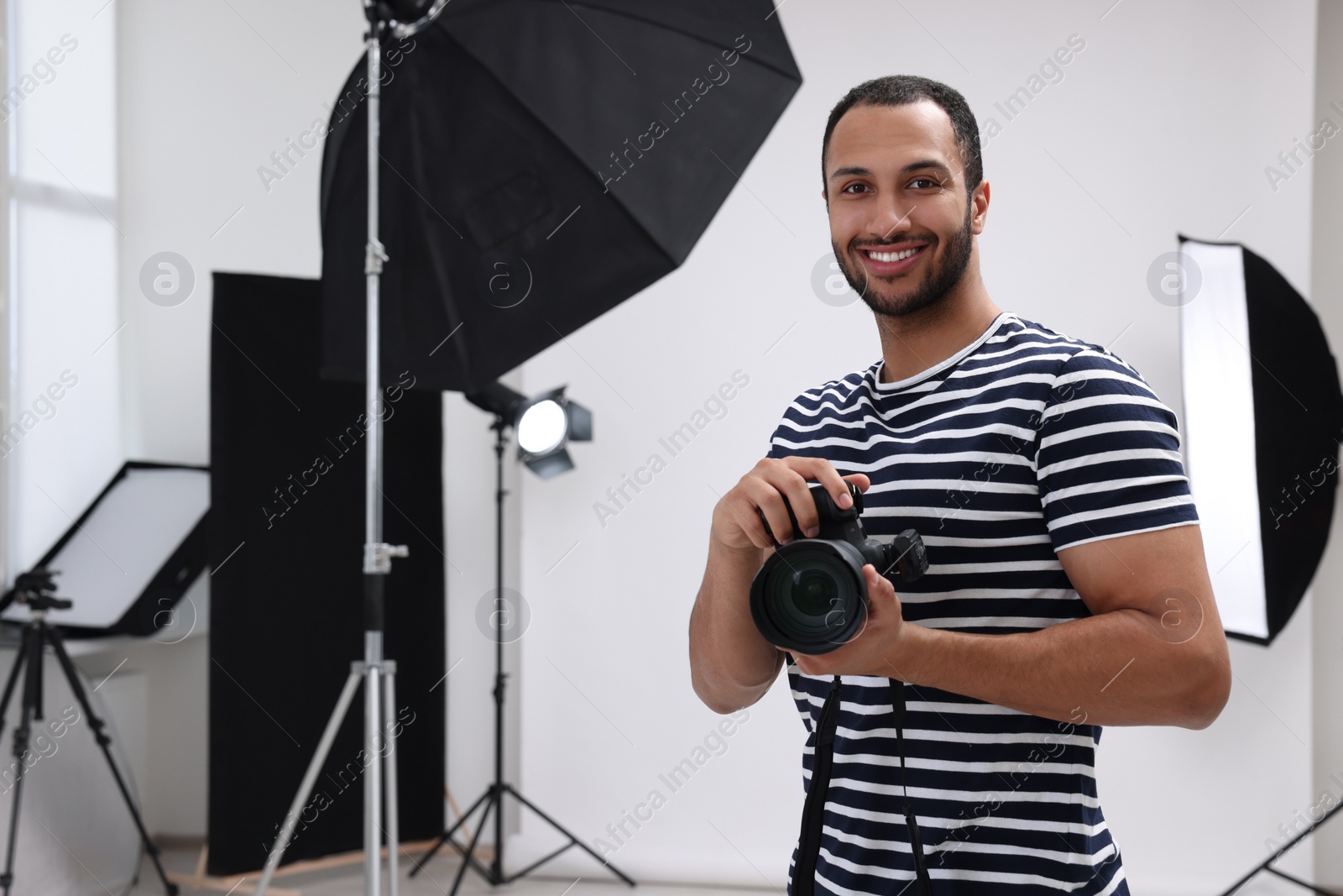 Photo of Young professional photographer with camera in modern photo studio, space for text