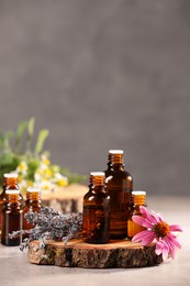 Photo of Bottles with essential oils and flowers on light table. Space for text
