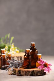 Bottles with essential oils and flowers on light table. Space for text