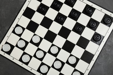 Photo of Checkerboard with game pieces on grey table, top view