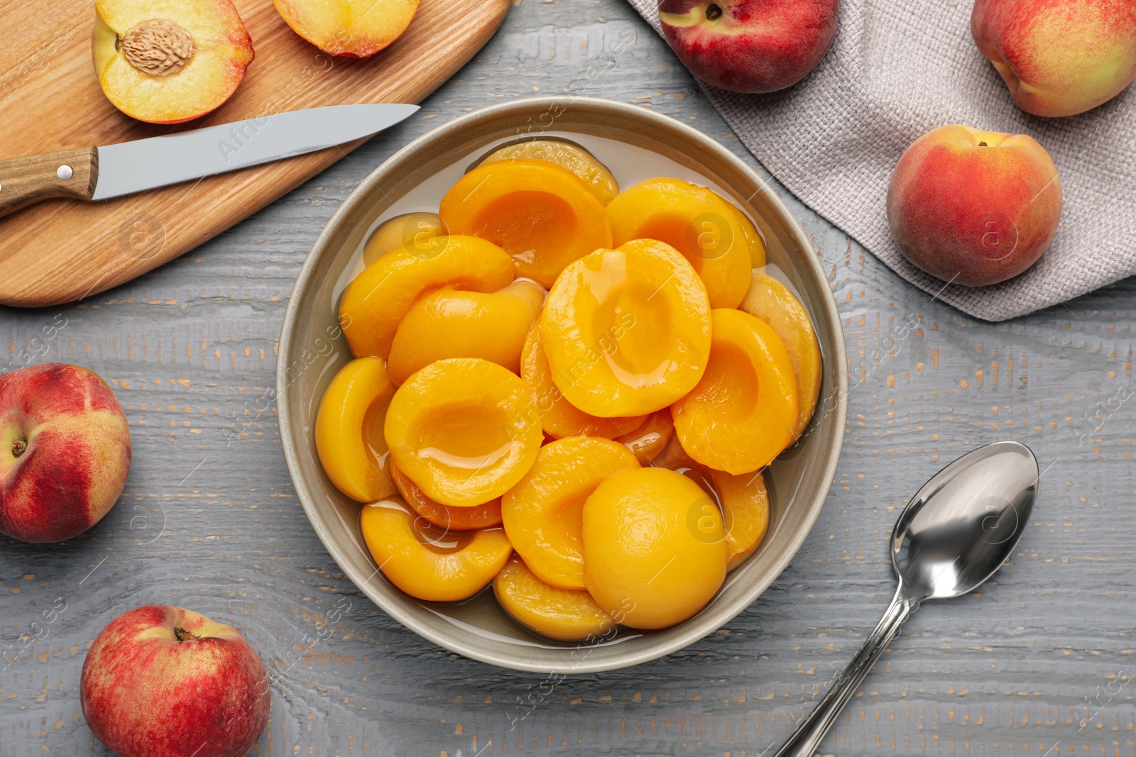 Photo of Canned peach halves on grey wooden table, flat lay