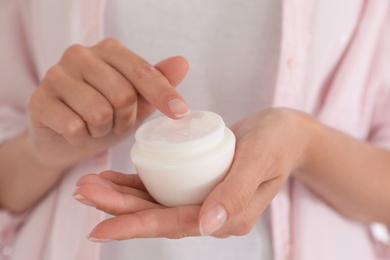 Photo of Woman holding open jar with cream, closeup