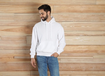 Photo of Portrait of young man in sweater at wooden wall. Mock up for design