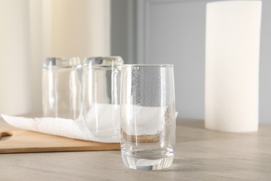 Photo of Clean glasses and paper towels on light wooden table