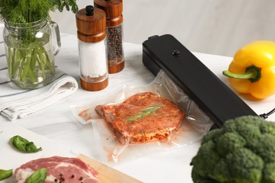 Photo of Sealer for vacuum packing with meat in plastic bag on white table indoors
