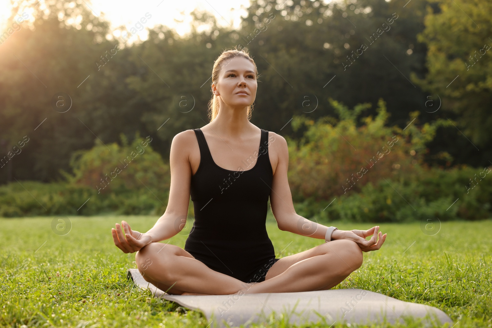 Photo of Beautiful woman practicing yoga on mat outdoors. Lotus pose