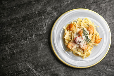 Photo of Delicious pasta with shrimps on black table, top view. Space for text