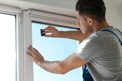 Photo of Professional worker tinting window with foil indoors