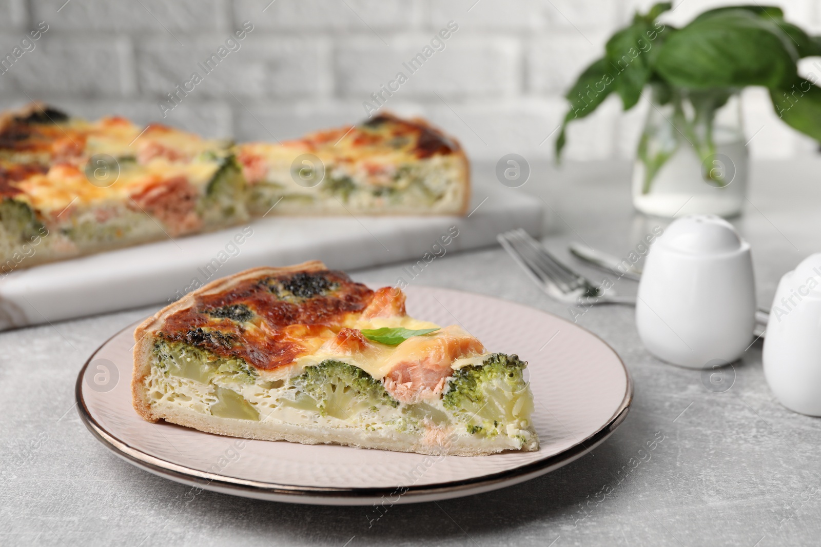 Photo of Piece of delicious homemade quiche with salmon and broccoli on light grey table