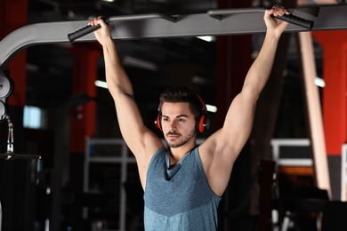 Young man with headphones listening to music and working out at gym