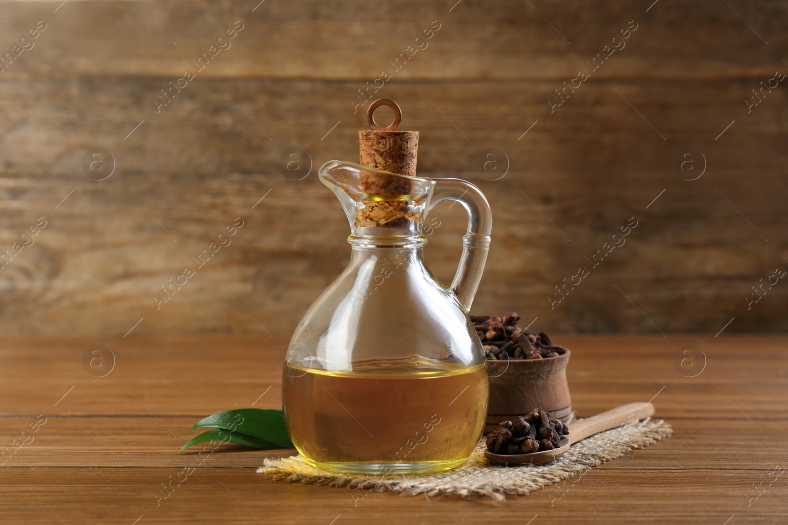 Photo of Essential oil and dried cloves on wooden table