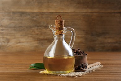 Essential oil and dried cloves on wooden table