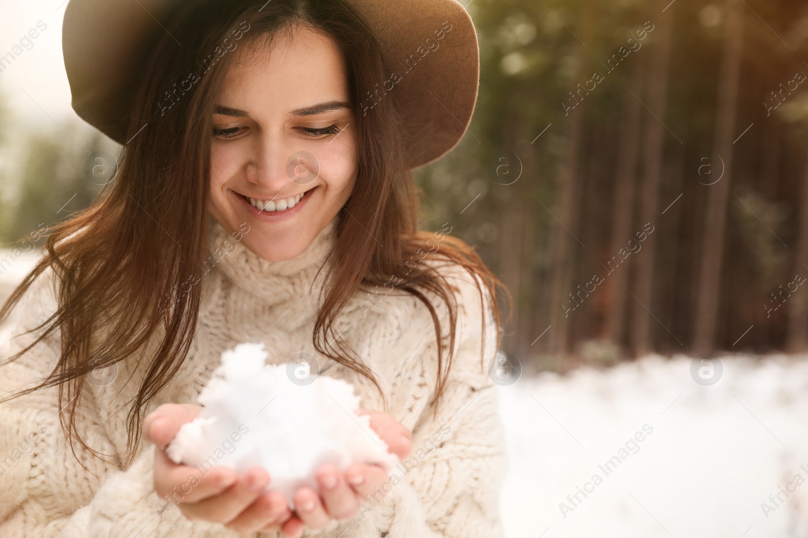 Photo of Young woman holding snow outdoors, space for text. Winter vacation