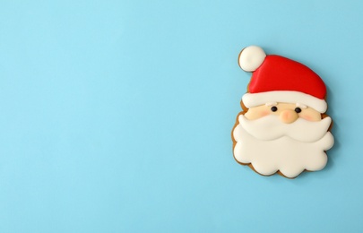 Christmas Santa Claus face shaped gingerbread cookie on light blue background, top view. Space for text