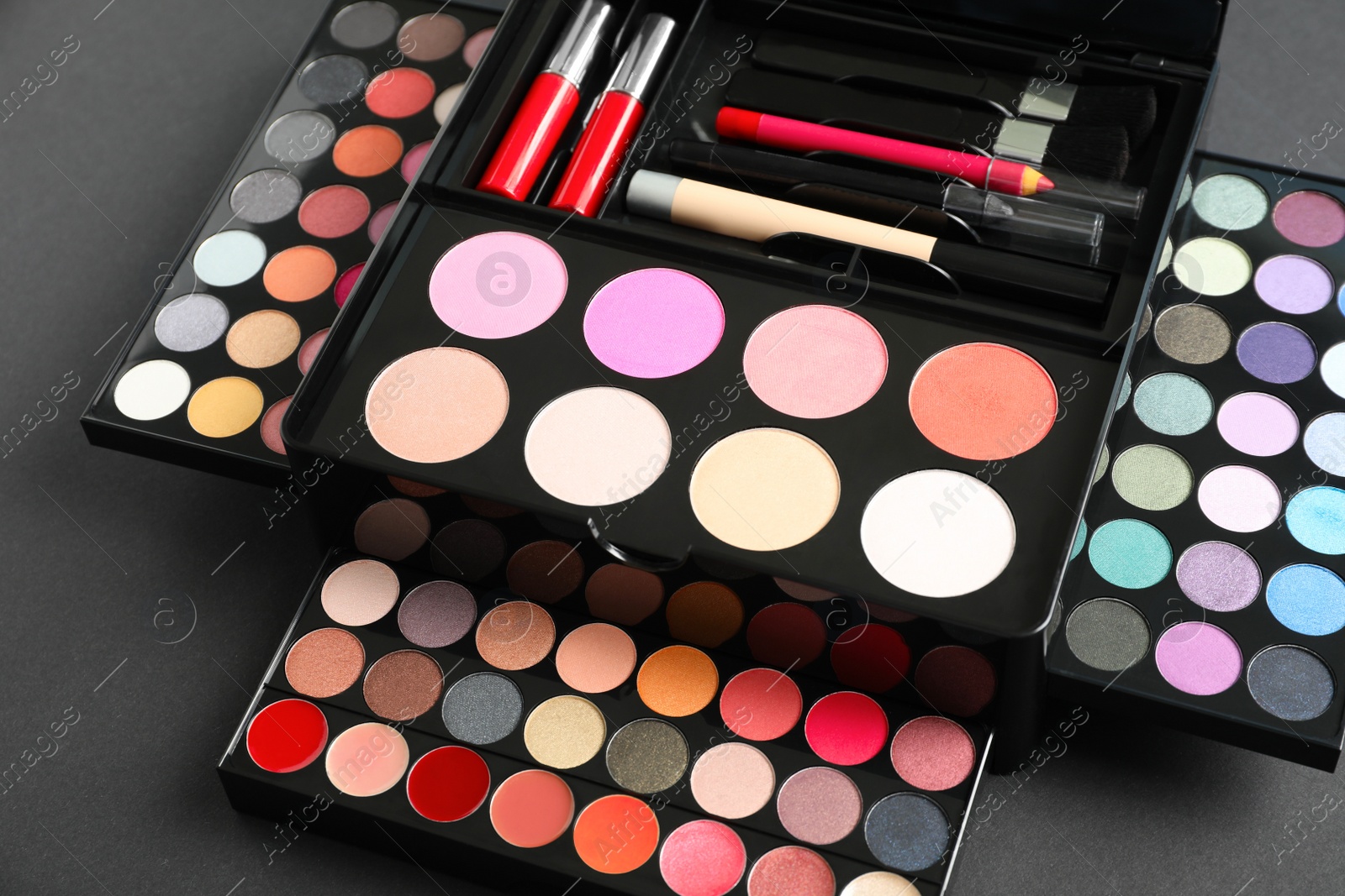 Photo of Large makeup case with different decorative cosmetics on dark background