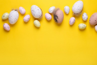 Photo of Many painted Easter eggs on yellow background, flat lay. Space for text