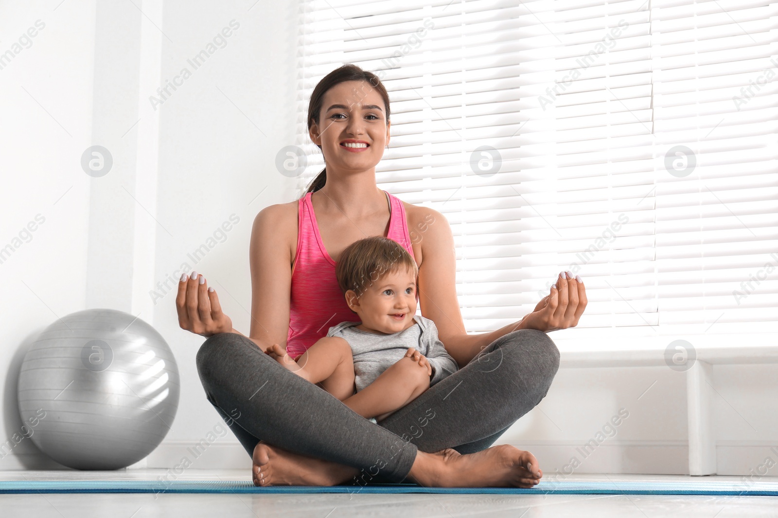 Photo of Young woman meditating with her son at home