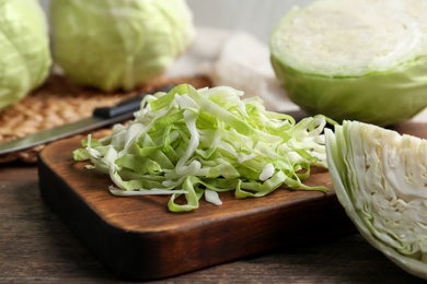 Photo of Fresh shredded cabbage on wooden table, closeup