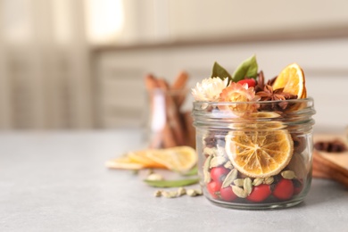 Photo of Aromatic potpourri in glass jar on light table. Space for text