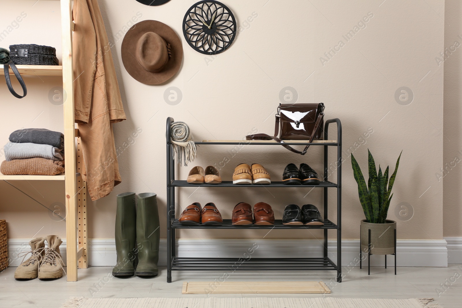 Photo of Rack with different shoes near beige wall in room