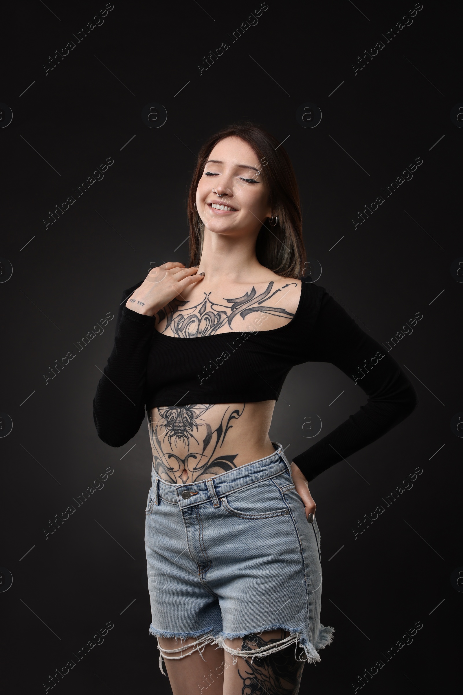 Photo of Portrait of smiling tattooed woman on black background