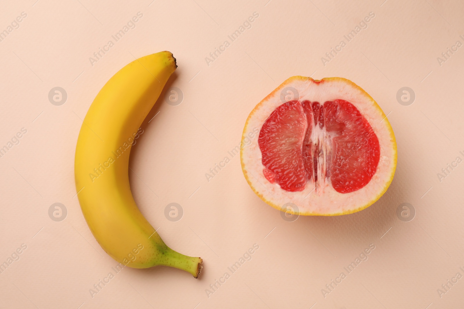 Photo of Banana and half of grapefruit on beige background, flat lay. Sex concept