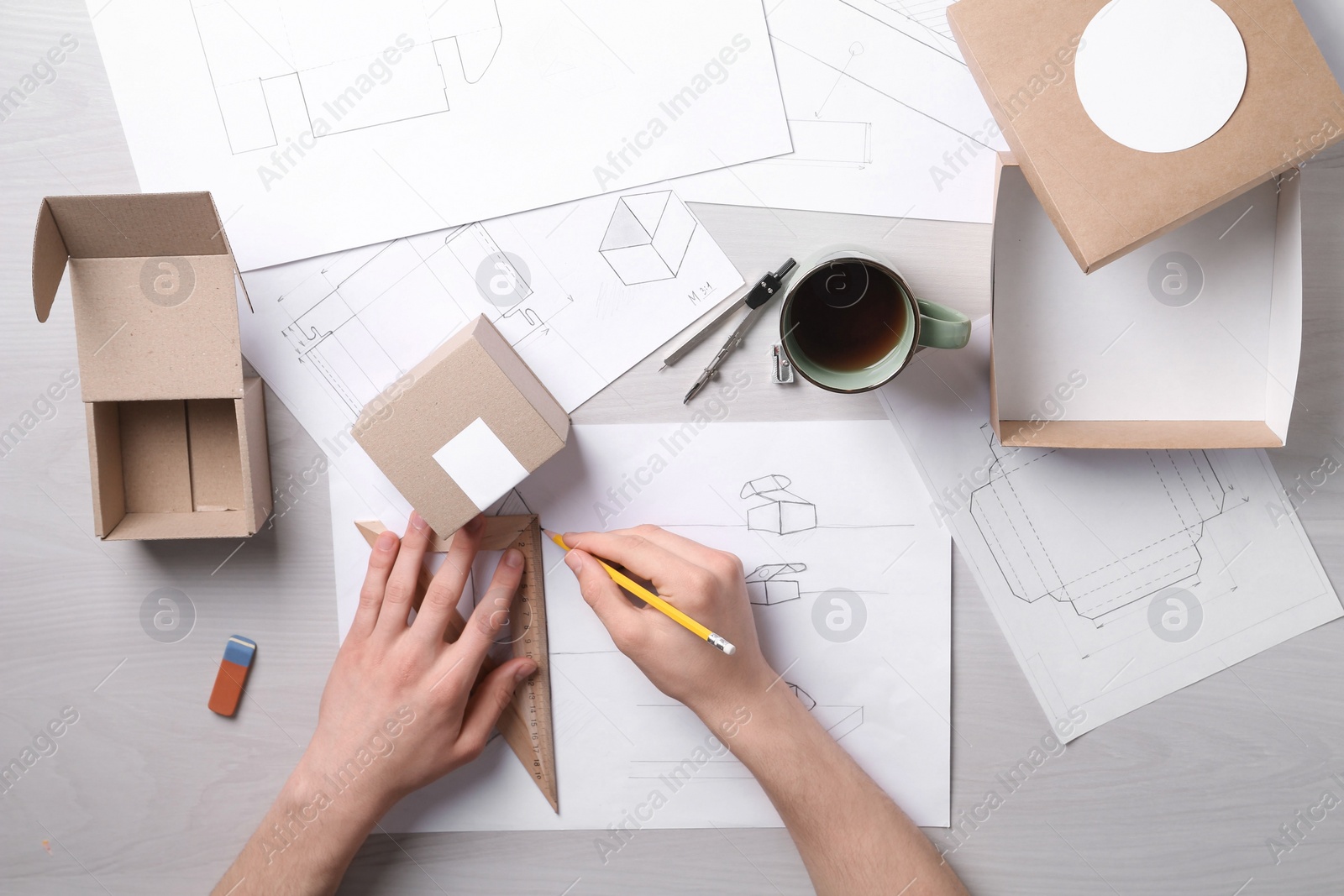 Photo of Man creating packaging design at light wooden table, top view