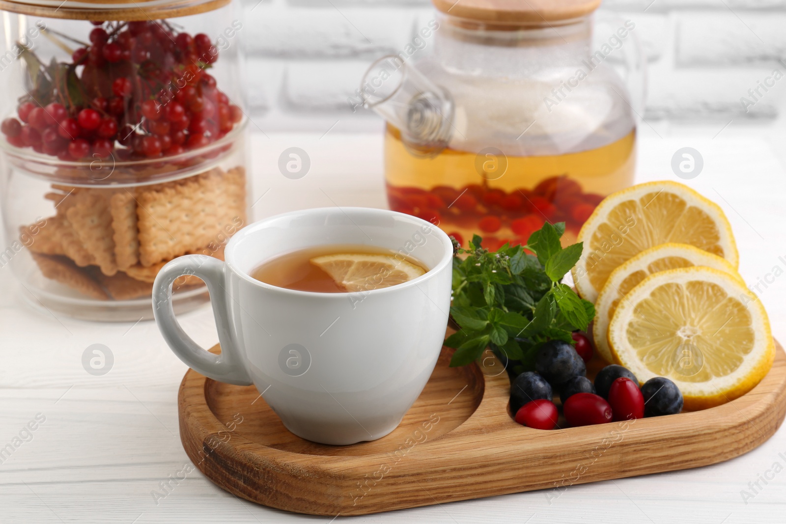 Photo of Cup with delicious immunity boosting tea and ingredients on white wooden table