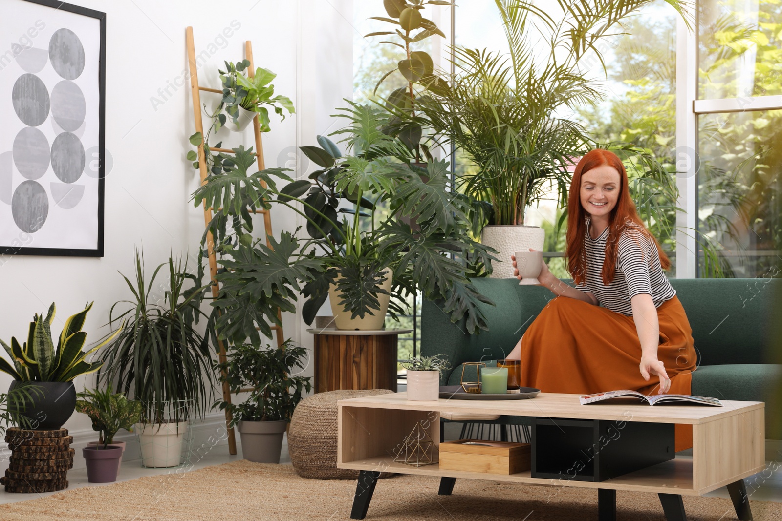 Photo of Beautiful woman with cup of tea on sofa in room