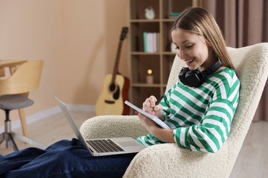 Photo of Online learning. Teenage girl with laptop and notepad at home