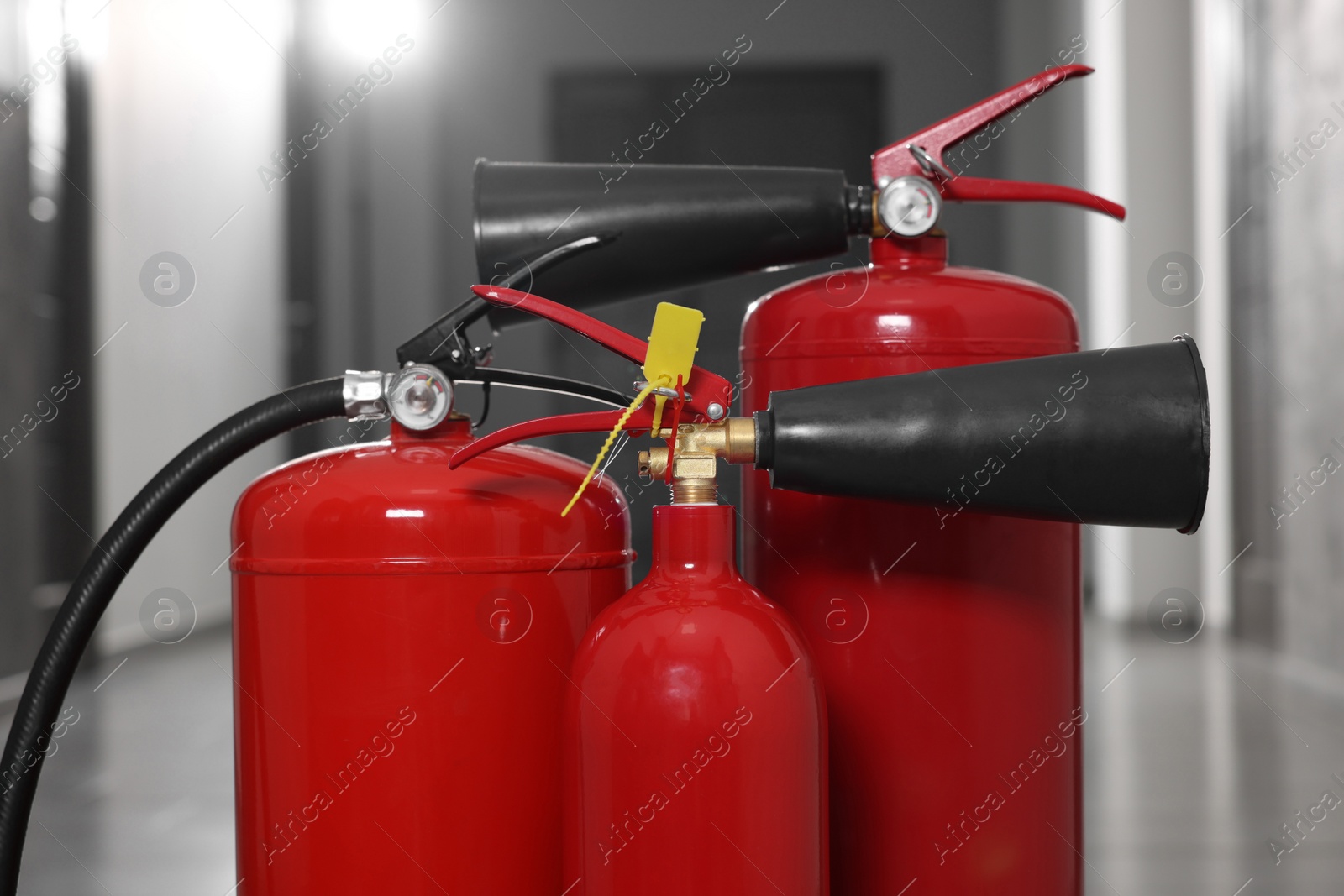 Photo of Three red fire extinguishers in hall, closeup