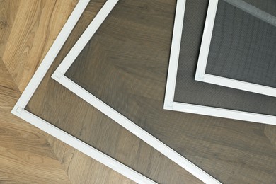 Set of window screens on wooden floor, flat lay