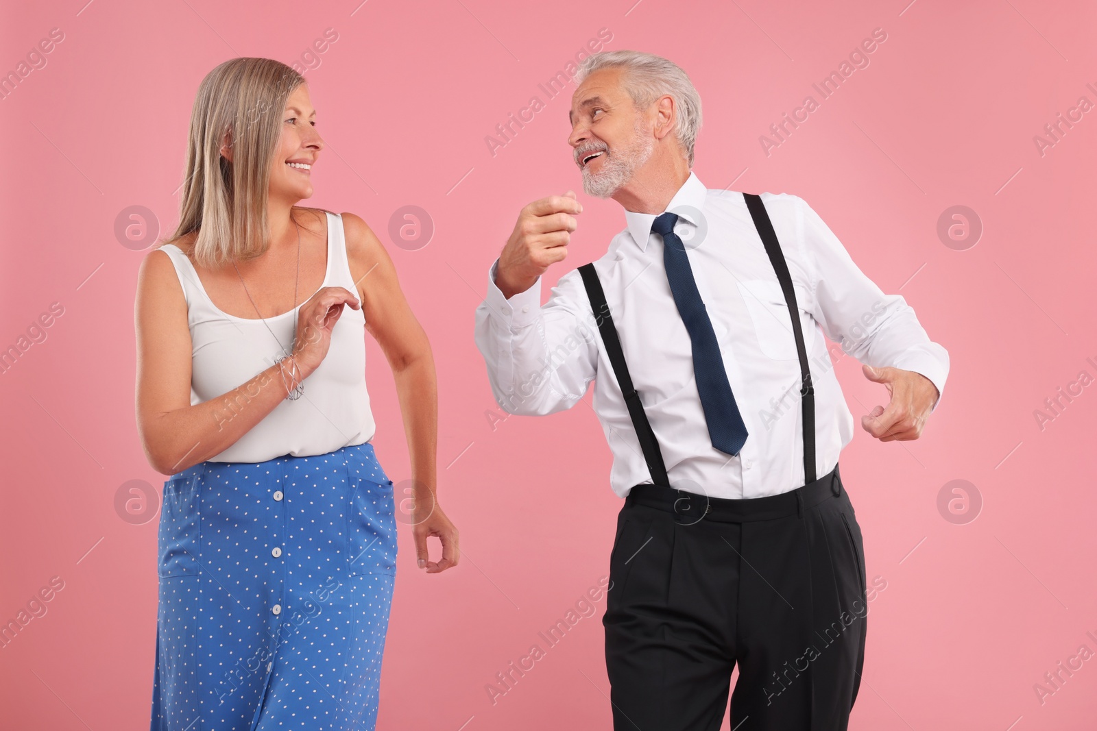 Photo of Senior couple dancing together on pink background