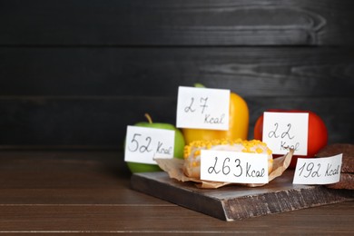 Food products with calorific value tags on wooden table, space for text. Weight loss concept