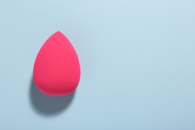 Photo of Pink makeup sponge on light blue background, top view. Space for text