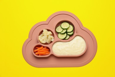 Healthy baby food in plate on yellow background, top view