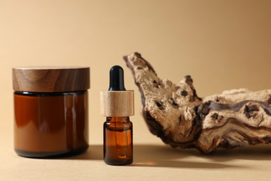 Photo of Jar with luxury cream, bottleessential oil and tree bark on dark beige background
