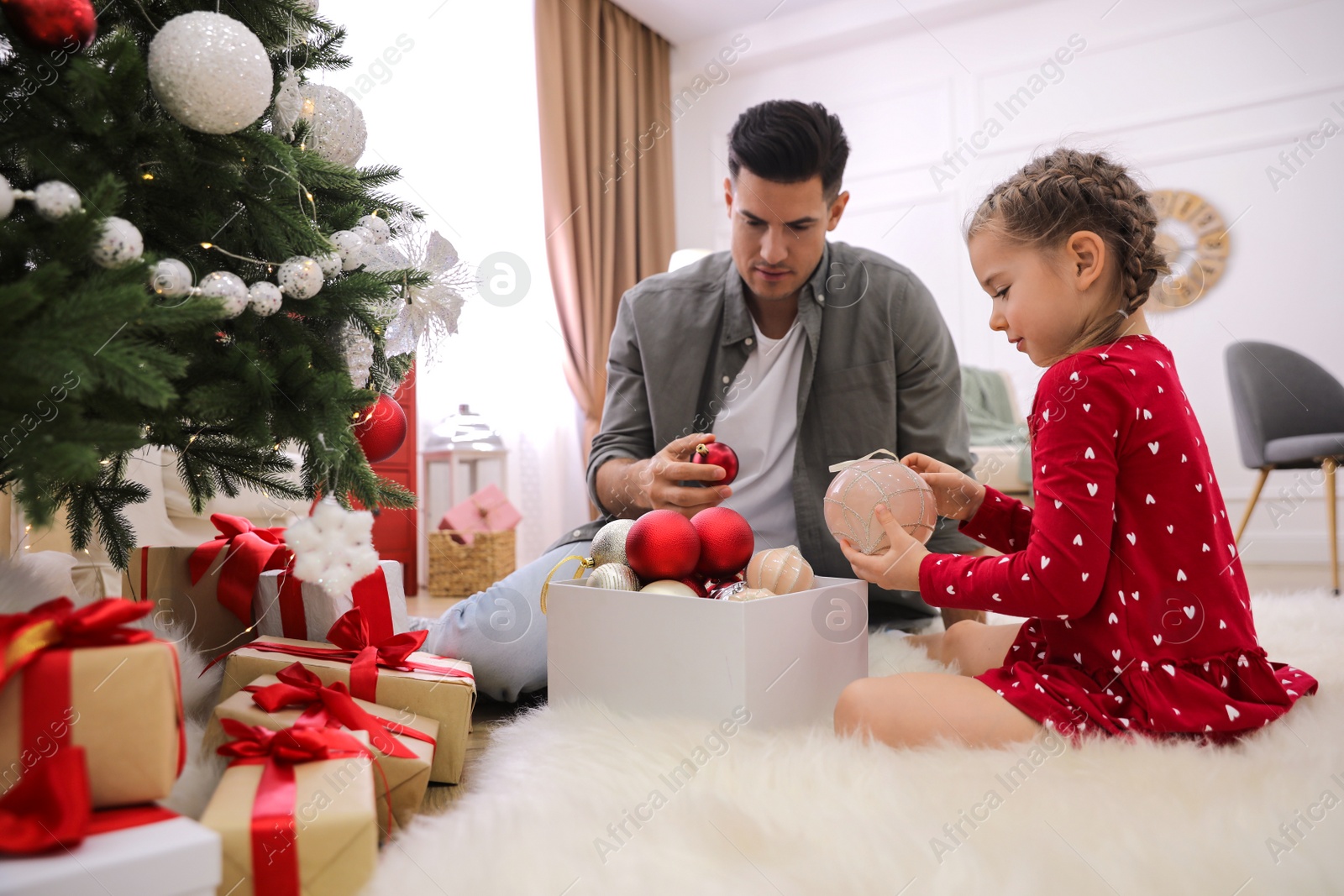 Photo of Father with his cute daughter decorating Christmas tree together at home