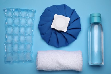 Bottle of water, cold compress, ice pack and towel on light blue background, flat lay. Heat stroke treatment