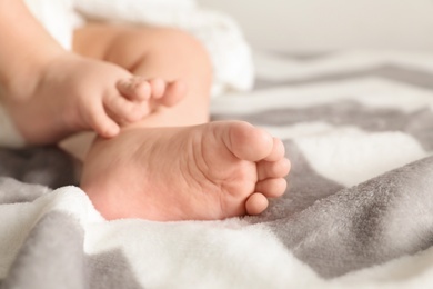 Photo of Little baby with cute feet on blanket, closeup. Space for text