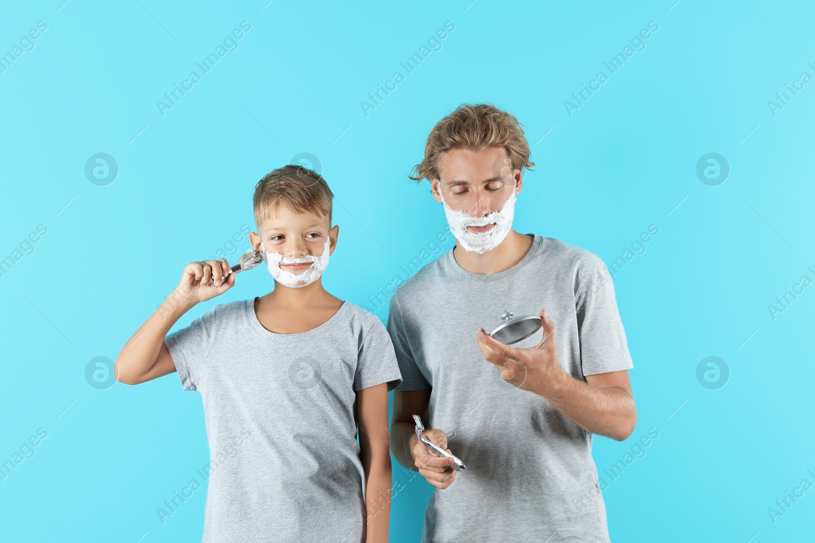 Photo of Father and son shaving together on color background