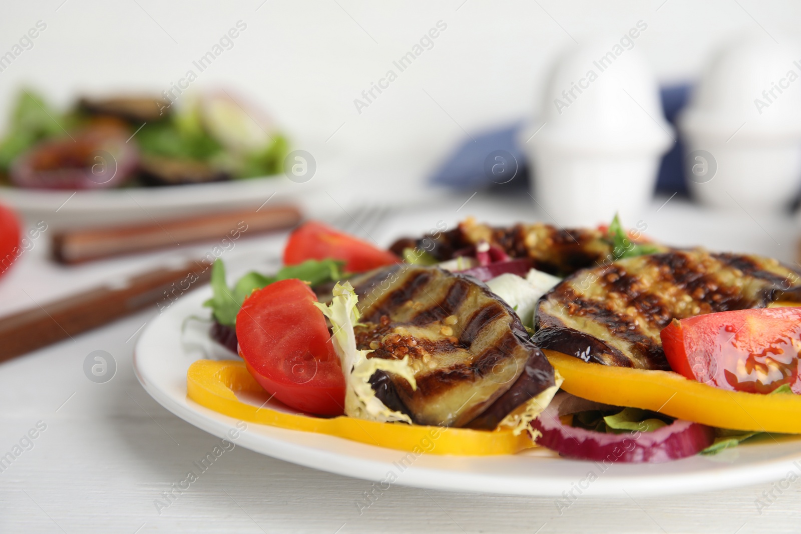 Photo of Delicious salad with roasted eggplant served on white table, closeup