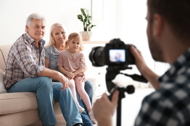 Photo of Professional photographer taking photo of family on sofa in studio