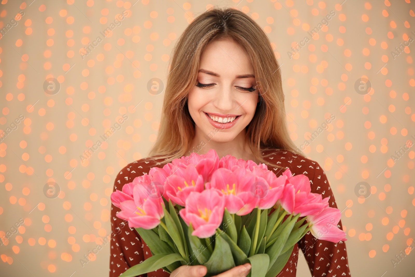 Photo of Portrait of smiling young girl with beautiful tulips on blurred background. International Women's Day