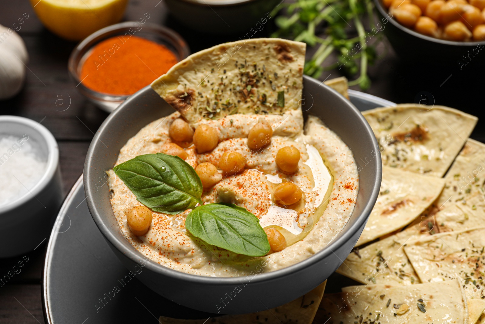 Photo of Delicious creamy hummus with chips and different ingredients on table, closeup