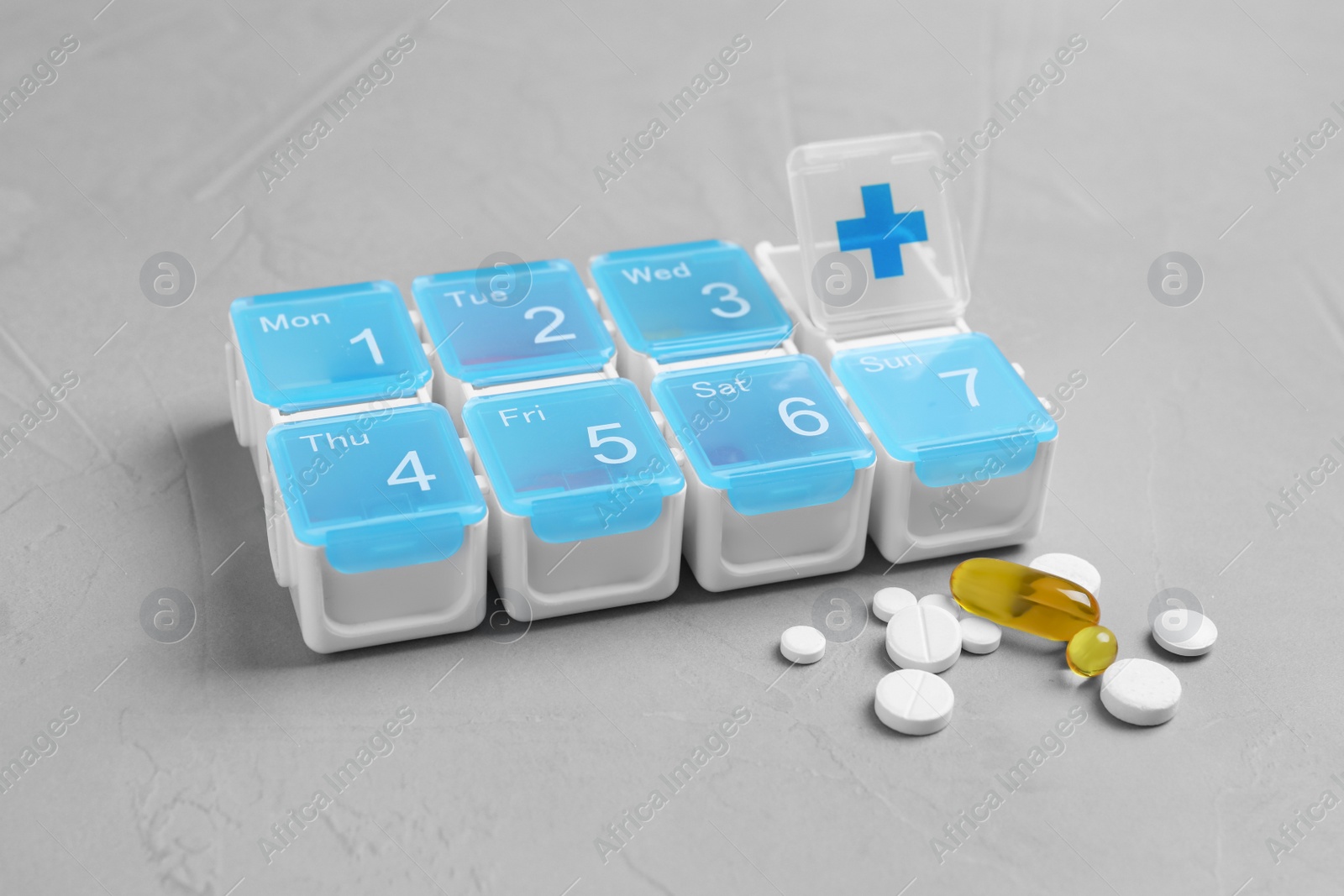 Photo of Weekly pill box with medicaments on grey table